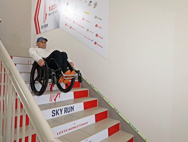 롯데월드타워에서 ‘휠체어 계단 내려가기’ 기네스 기록에 도전 중인 하키도쿠 선수가 한 계단 한 계단 조심스럽게 내려가고 있다.